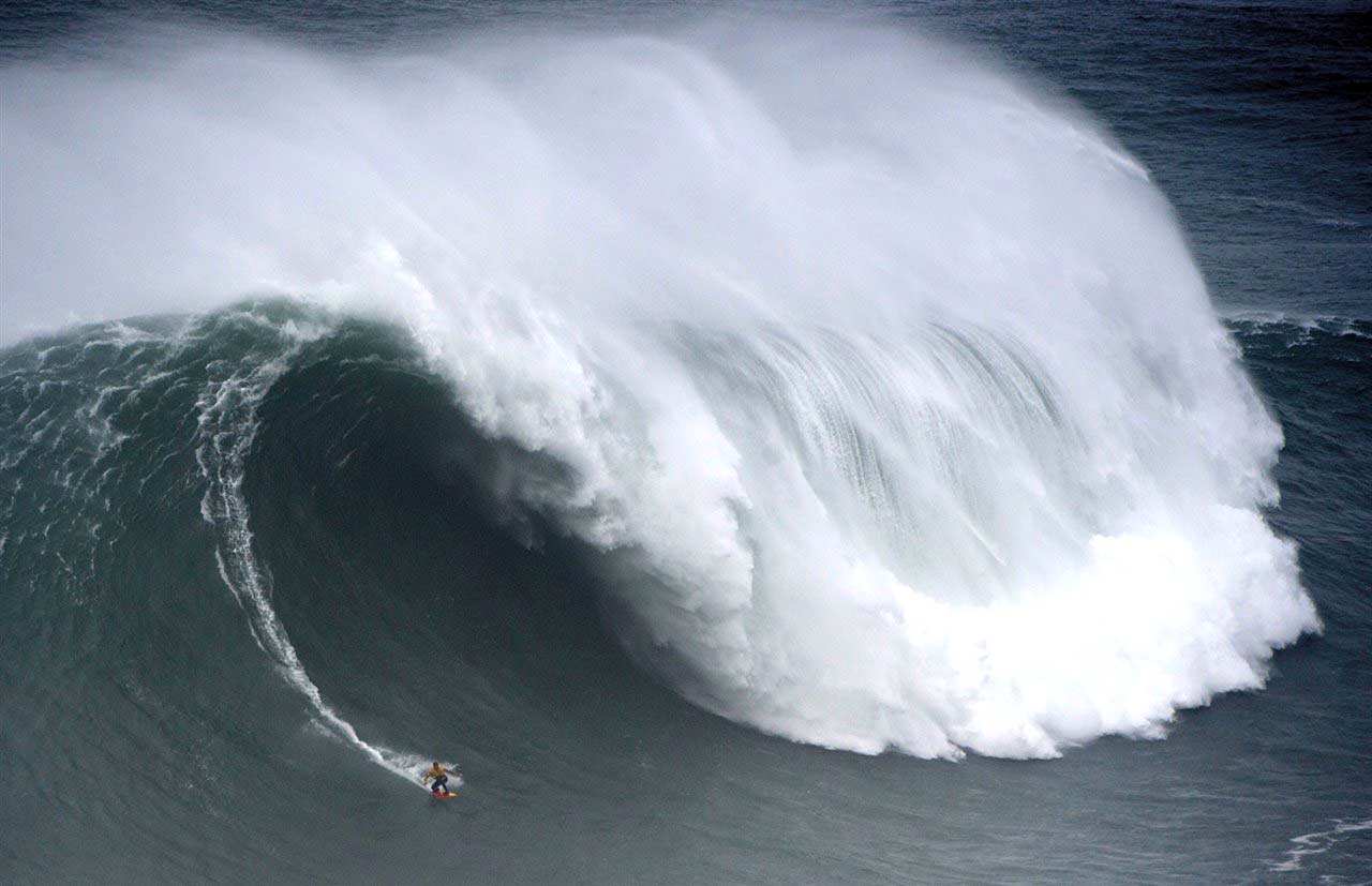 Ola gigante en Nazaré con un surfista en Portugal